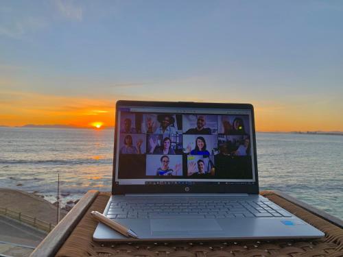 a laptop computer sitting on a table next to the ocean at 185 on BEACH Boutique Suites in Gordonʼs Bay