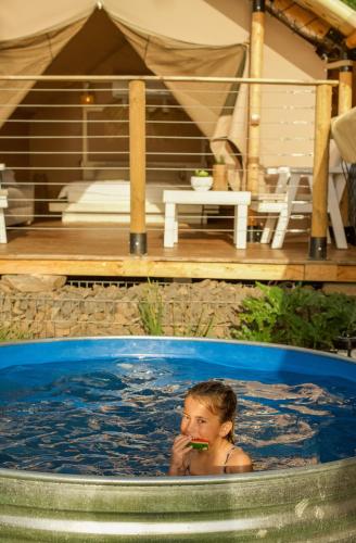 a young child sitting in a swimming pool at Sky Glamping boutique in Moshav Ramot