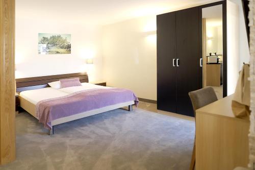 a bedroom with a bed and a black cabinet at Hotel Villa Margaret in Malinska