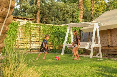 two children playing with a soccer ball in the yard at Sky Glamping boutique in Moshav Ramot