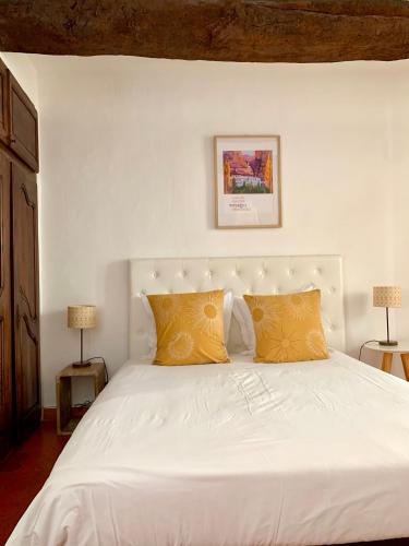 - un lit blanc avec 2 oreillers jaunes dans l'établissement Le 1835, Studio Ambre-Jaune, à Moustiers-Sainte-Marie