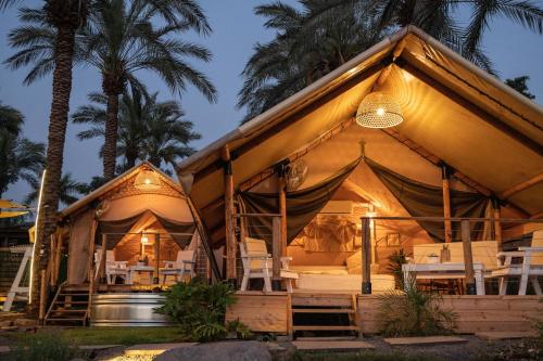 a resort with a tent with chairs and palm trees at Sky Glamping boutique in Moshav Ramot