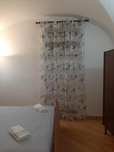 a bedroom with a bed and a curtain with two towels at Alloggi Piazza Umberto Primo in Pacentro