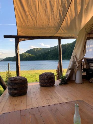 a tent with two tires on a wooden deck with a lake at Luxury Lake House & Glamping in Teşila