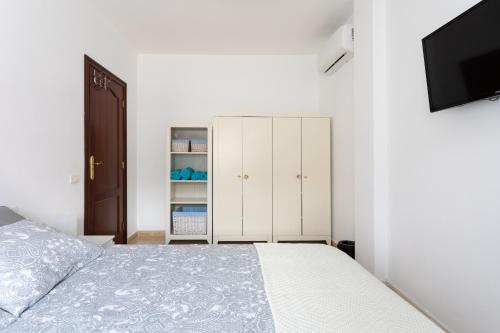 1 dormitorio blanco con 1 cama y TV en Home2Book Sea Side Charco Azul Pool Apartment Wifi, en San Andres y Sauces
