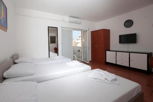 a bedroom with three white beds and a television at Apartments Peris Resort in Novalja