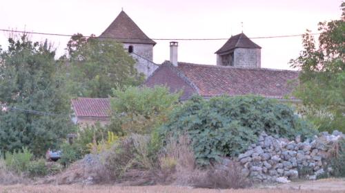 a yard with a stone wall and a house at L'Echappée Belle Périgord in Cercles
