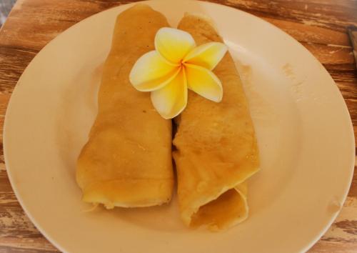 een wit bord met een calzone met een bloem erop bij The Pancor Jungle Resort in Nusa Penida