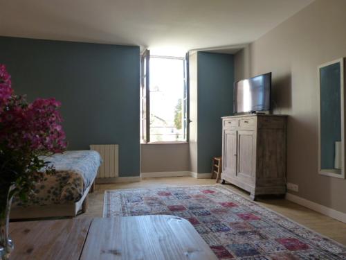 a living room with a couch and a tv at L'Echappée Belle Périgord in Cercles