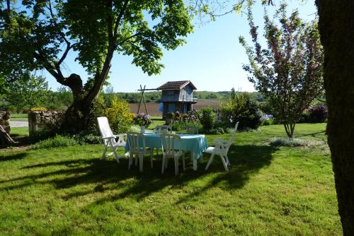 a table and chairs in a yard with a house at L'Echappée Belle Périgord in Cercles