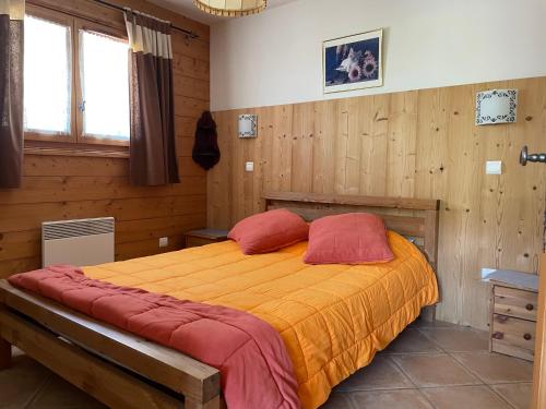 a bedroom with a bed with orange sheets and red pillows at Le Lessy M2 in Le Grand-Bornand