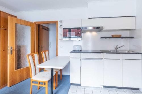 - une cuisine avec des placards blancs, une table et des chaises dans l'établissement Fischerhus Wohnung 4, à Cuxhaven