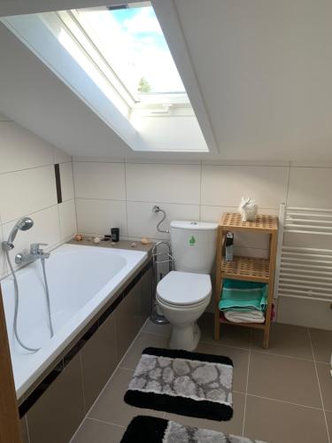 a bathroom with a toilet and a bath tub and a skylight at Ferienwohnung Allgäuglück in Oberreute
