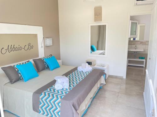 ein Schlafzimmer mit einem großen Bett mit blauen Kissen in der Unterkunft Resort Abbaia Ba in Budoni