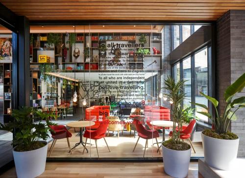 a restaurant with red chairs and tables in front of a window at citizenM Seattle Pioneer Square in Seattle