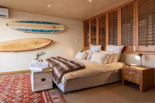 Un dormitorio con una cama y una tabla de surf en la pared. en Dolphin Sunrise, en Jeffreys Bay