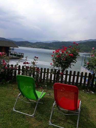 two chairs sitting in the grass next to a body of water at Lejla apartmani - Jablaničko jezero in Konjic