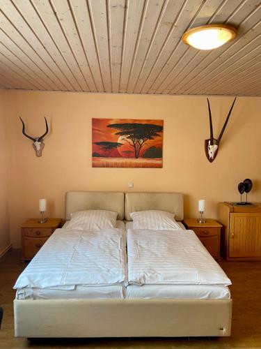Jägerhof Ostsee في Holm: غرفة نوم بسرير ابيض مع طاولتين ولوحة