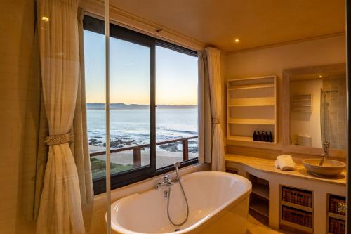 Un baño con bañera y una gran ventana. en Dolphin Sunrise, en Jeffreys Bay