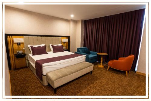 a hotel room with a bed and a blue chair at Premium Hotel Ganja in Ganja