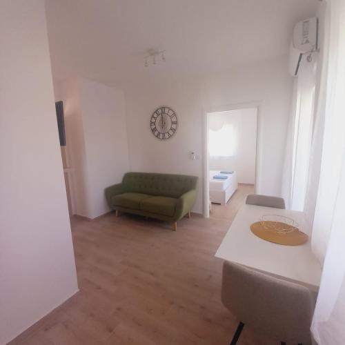 a living room with a green couch and a clock on the wall at Apartments M & L Murter in Murter