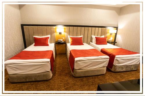 two beds in a hotel room with red pillows at Premium Hotel Ganja in Ganja