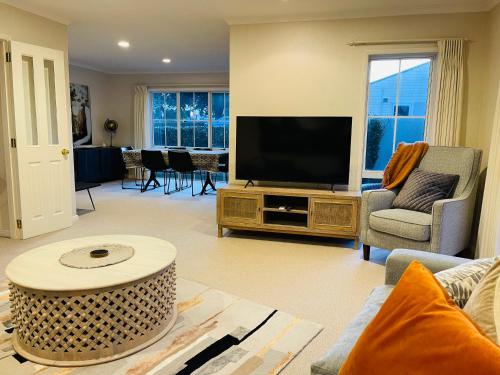 a living room with a flat screen tv on a table at TAURANGA CITY CBD 5TH AVE Elegant Entire Home in Tauranga