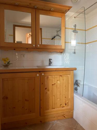 een badkamer met houten kasten, een wastafel en een bad bij Le Lessy M4 in Le Grand-Bornand