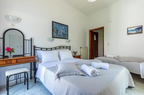 a bedroom with two beds and a desk and a mirror at Regina Hotel in Skopelos Town
