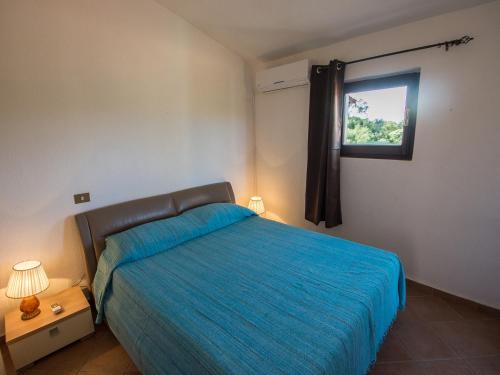1 dormitorio con 1 cama con edredón azul y ventana en Appartamenti Il Borgo 400 metri dal mare, en Porto Pollo