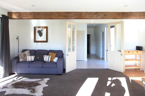 ein Wohnzimmer mit einer blauen Couch und einem Flur in der Unterkunft Sunny Lakeside Haven in Queenstown
