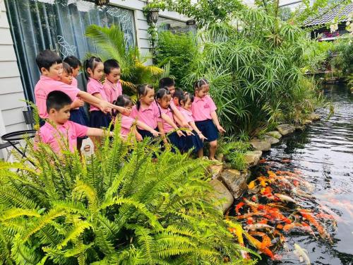 a group of children in pink shirts standing next to a pond at Window Homestay in Kon Tum