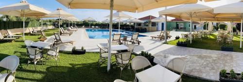 a group of tables and chairs with umbrellas next to a pool at Stomio Villague in Filiatra