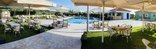 a group of tables and chairs with umbrellas next to a pool at Stomio Villague in Filiatra