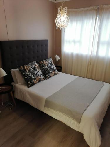 a bedroom with a large bed with a chandelier at Ons Strandhuisie N5 in Pearly Beach in Pearly Beach