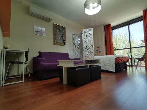 a living room with a purple couch and a table at Madrid AlcoTour Apto trabajo y relax in Alcobendas