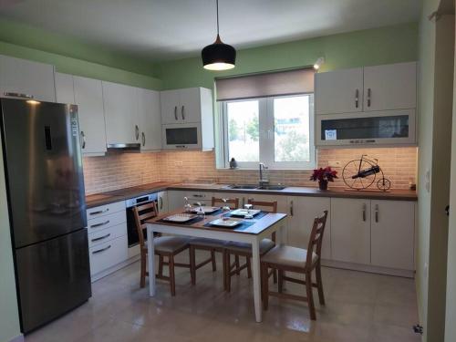 een keuken met een tafel en stoelen en een koelkast bij The Bright House a two-storey maisonette in Loutraki in Loutraki