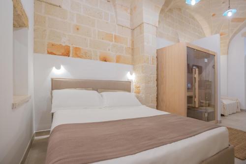 a bedroom with a large bed with a stone wall at Filia Solis - Old Town SUITEs & SPA in Brindisi
