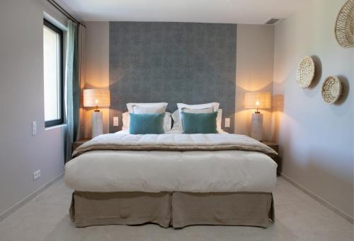a bedroom with a large bed with two blue pillows at Domaine de Montine Chambres de Charme in Grignan
