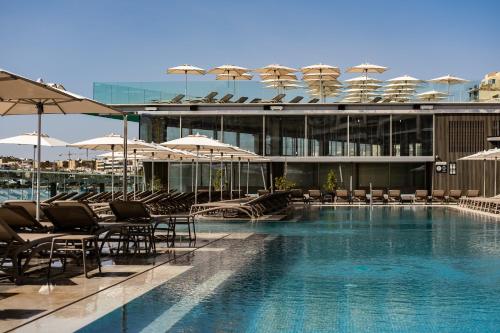 a swimming pool with chairs and umbrellas in a building at Waterfront in Sliema