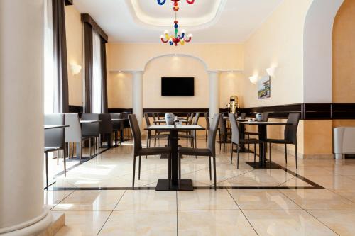 una sala da pranzo con tavoli, sedie e lampadario a braccio di Mokinba Hotels Baviera a Milano
