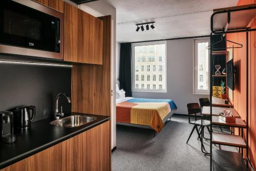 a hotel room with a bed and a kitchen with a sink at The Social Hub Delft in Delft