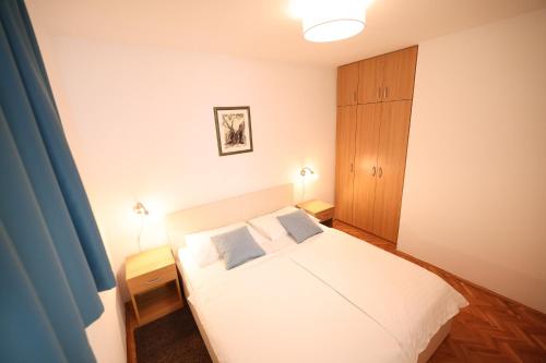 a bedroom with a white bed with two blue pillows at Hotel Lucija in Posedarje