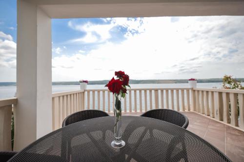 a vase with a rose on a table on a balcony at Hotel Lucija in Posedarje