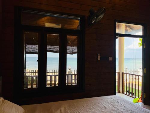 a bedroom with windows with a view of the ocean at Janas Blue Water Corner in Trincomalee