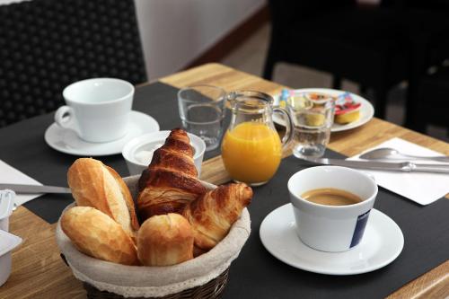 een tafel met een mand met gebak en een kopje koffie bij Hôtel Le Chalet in Valras-Plage