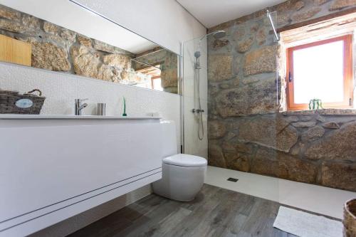 a bathroom with a stone wall and a toilet and a sink at Quinta da Bela vista in Celorico de Basto