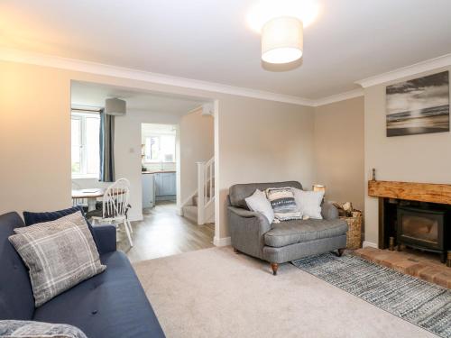 uma sala de estar com um sofá, uma cadeira e uma lareira em 3 The Cottages em Great Yarmouth