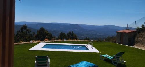 a yard with a swimming pool and two lawn chairs at Bungalow da Bela Vista, Ribas, Celorico de Basto in Celorico de Basto