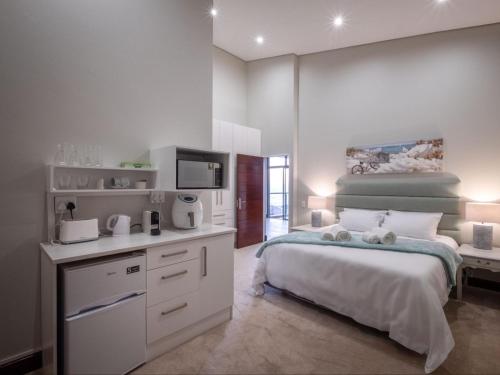 a white bedroom with a bed and a kitchen at Anchor's Haven Hersham in Groot Brak Rivier